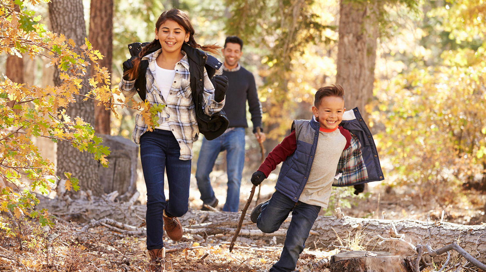 Children in a forest running to camera, father looking on